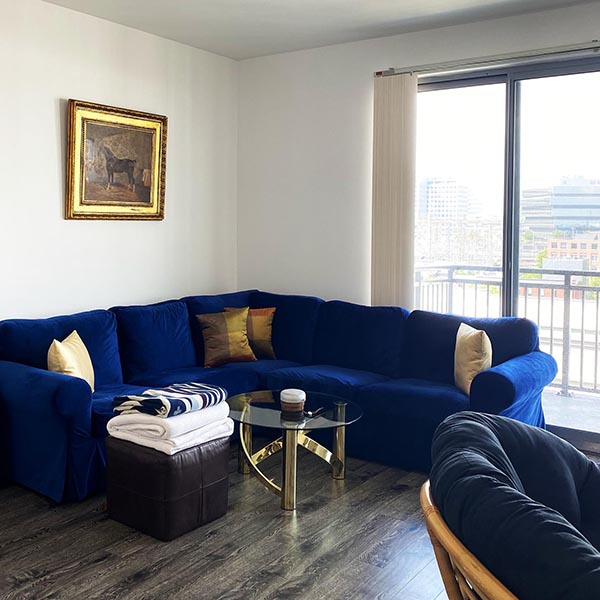 Retro glam #LKRB living room with an IKEA sofa, antique oil painting, customized designer pillows, mid-century coffee table, EQ3 leather ottoman, Pendleton wool blanket, Ralph Lauren throw, and Bang & Olufsen Bluetooth speaker | Photo by Mir Martz