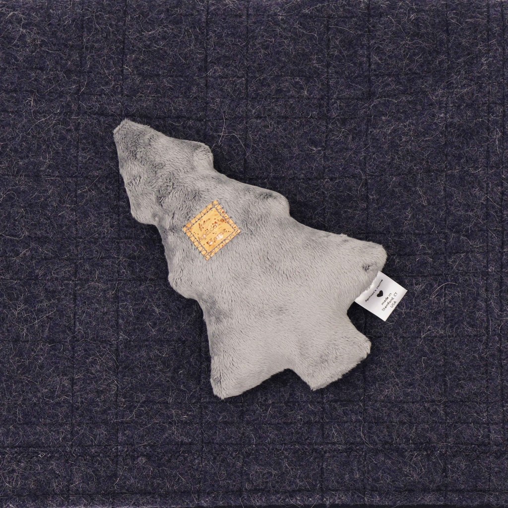 Detail of a Big Christmas Tree Dog Toy in Silver Plush on top of the navy washable alpaca wool used in The Chalet Dog Blanket | Photo by Mir Martz